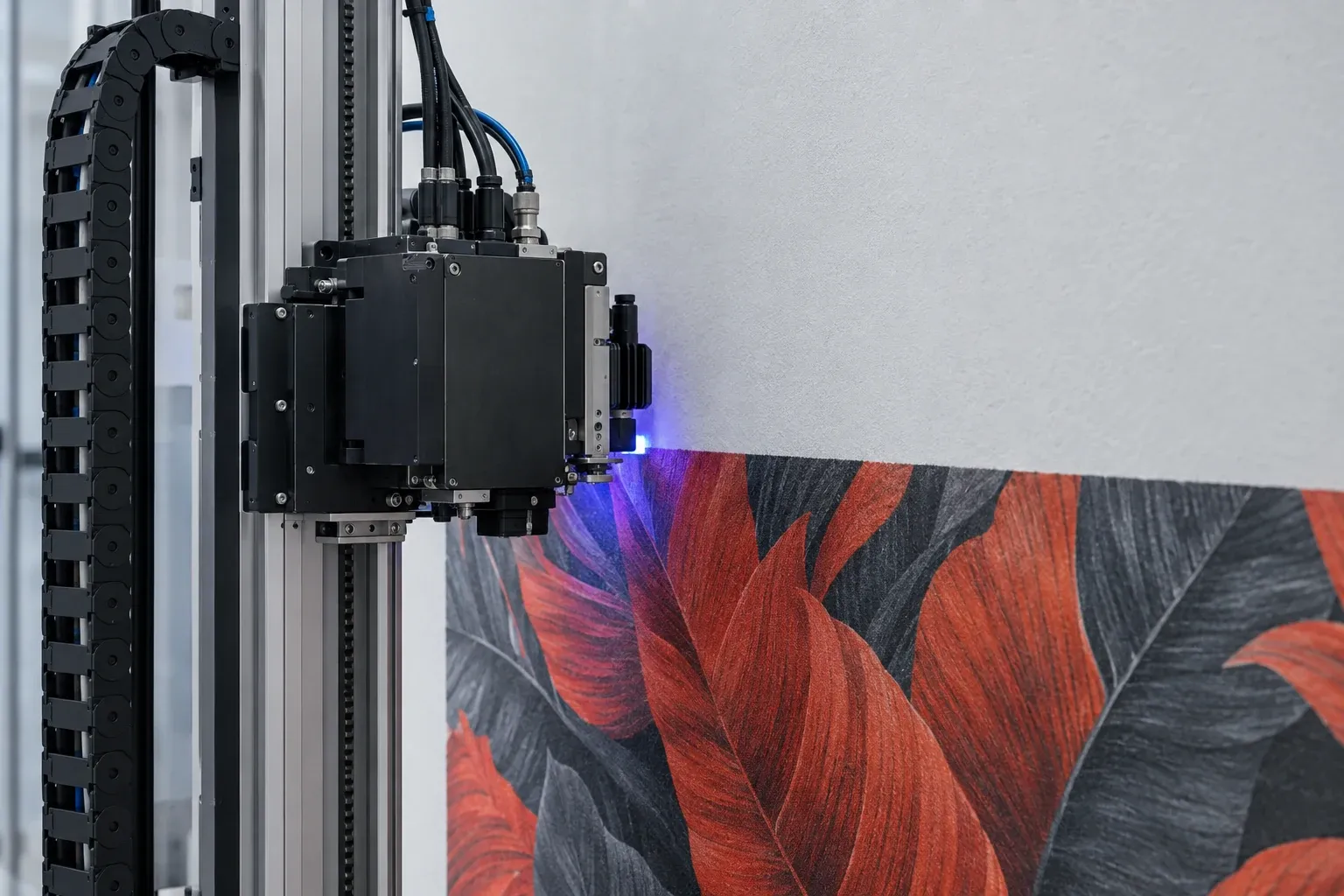 Tête d’impression murale sur son mât en aluminium, lumière UV bleue au contact du mur, feuillage vermillon et anthracite déjà imprimé dessous